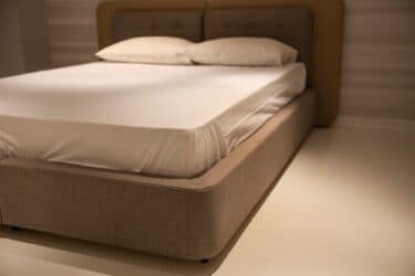 Cama minimalista con ropa de cama blanca